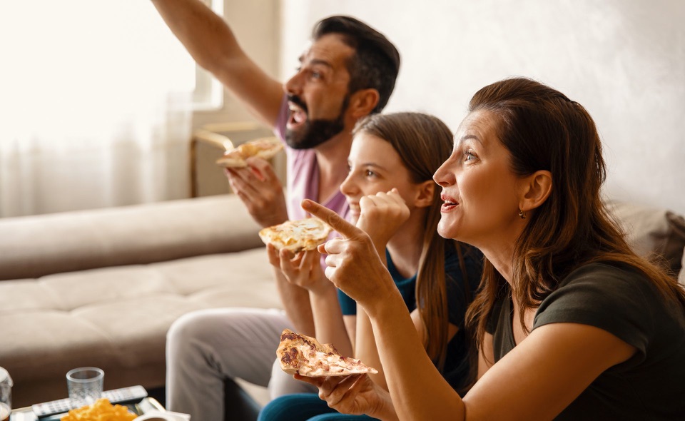 Family enjoying a flammekueche in front of the television
